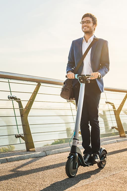 jeune homme en costume faisant du scooter electrique