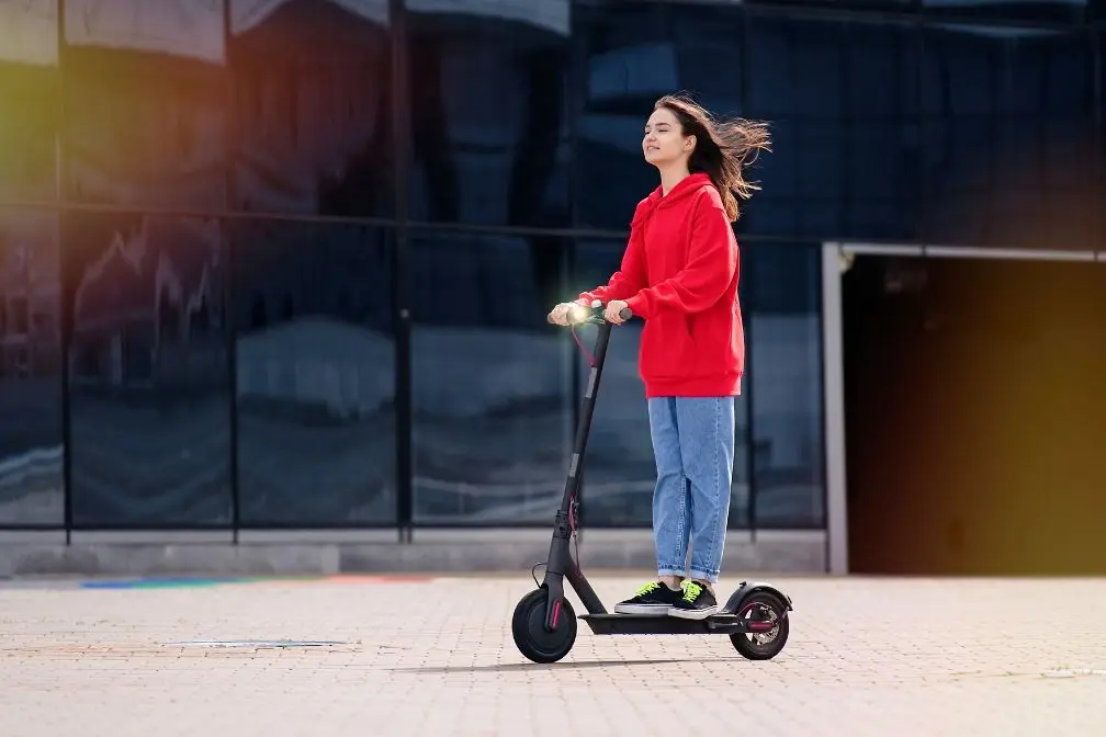 jeune fille qui se déplace avec sa trottinette électrique